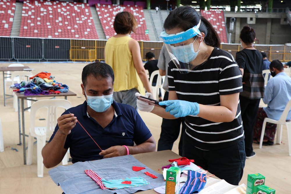 新加坡国际基金会代表黄小姐（右）抽空与客工一起参与缝纫。 摄 / 连雅慧