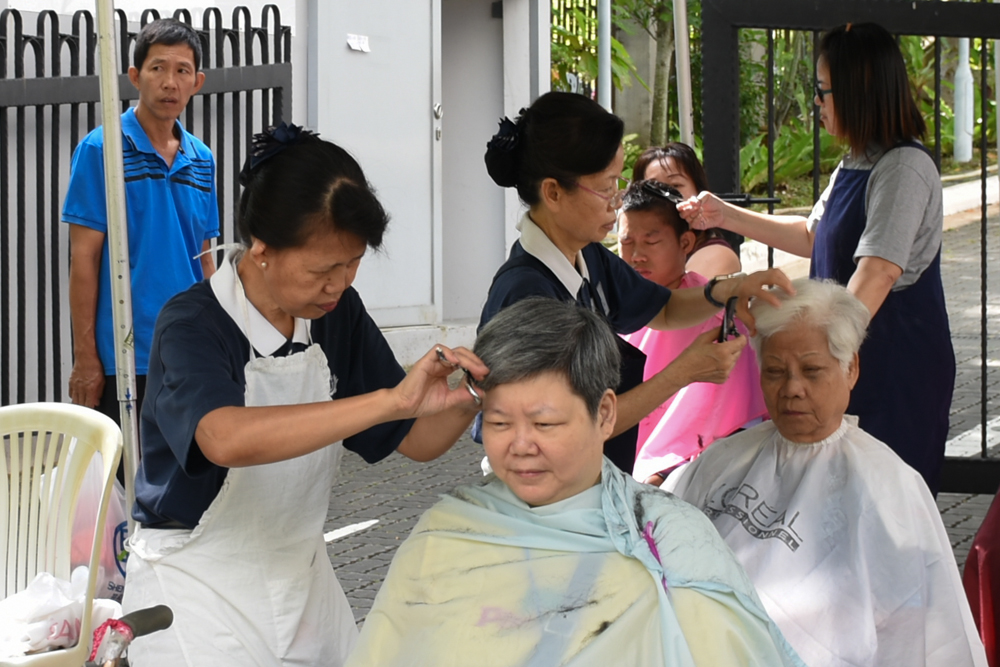 Aid recipients getting their free haircuts outside the Jing Si Hall before the celebration commences. (Photo by Audrey Phang)