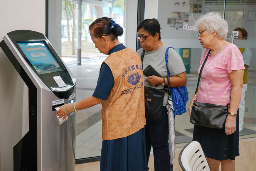 A digital kiosk at the free clinic allows patients to scan their ID cards and obtain their queue numbers. (Photo by Chan May Ching)